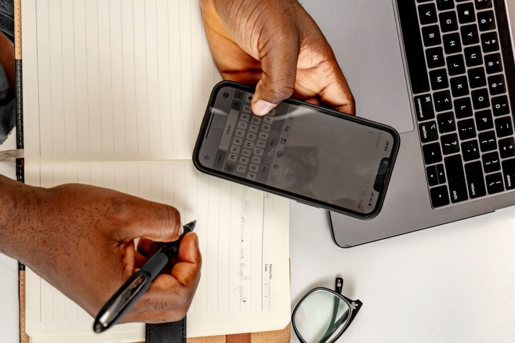 Hände tippen eine höfliche Nachricht auf dem Smartphone neben Notizbuch