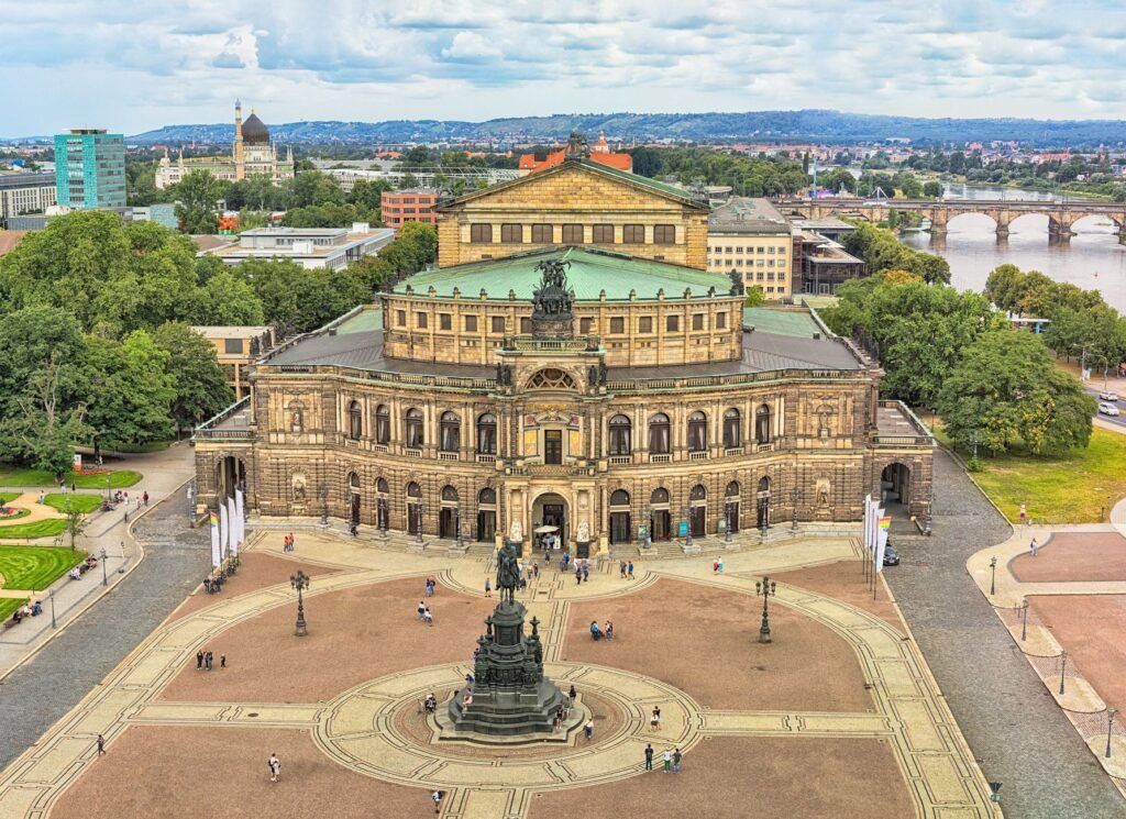 Luftaufnahme der historischen Semperoper Dresden im Sommer, mit dem Theaterplatz und der umliegenden Stadtlandschaft.